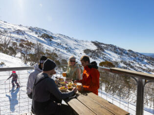 friends dining on the outdoor deck of Black Sallees, Thredbo